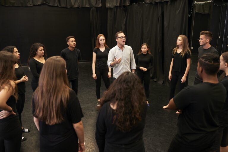 Teacher With Male And Female Drama Students At Performing Arts School In Studio Improvisation Class