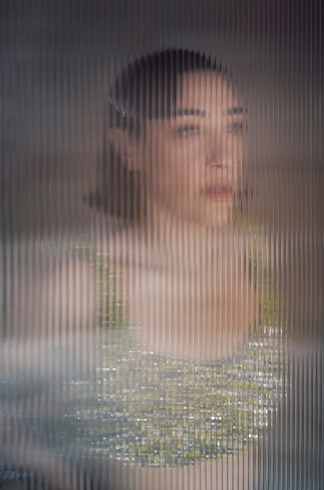 Portrait of Mia Moretti seen through textured reeded glass