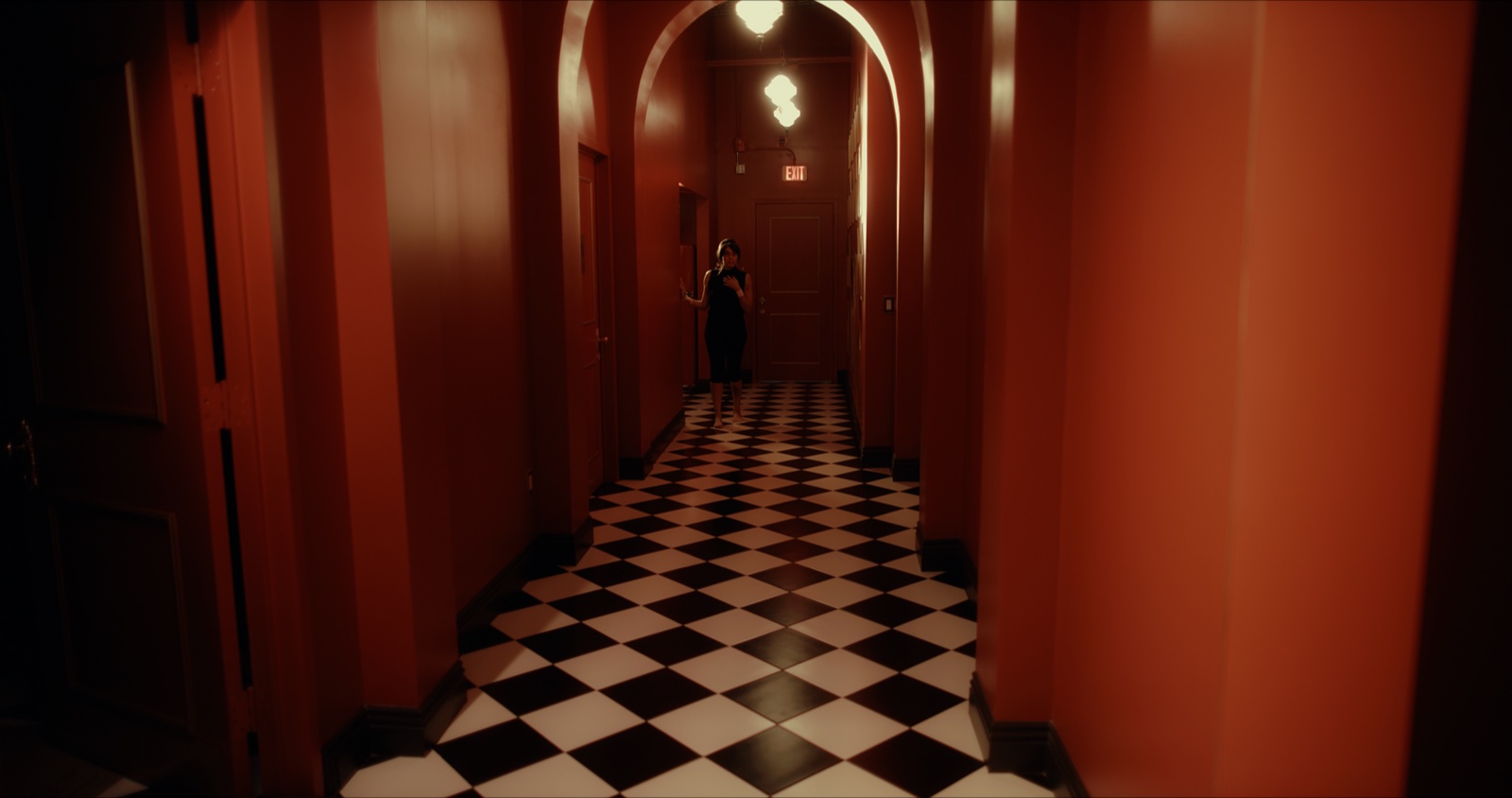 A deep red hallway with a black-and-white checkerboard floor from the short film Always Enough
