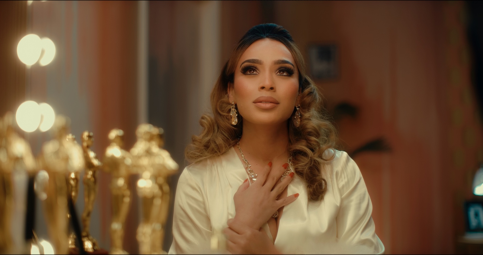 Seraphina at a mirror-lit vanity surrounded by gold statuettes in the short film Always Enough
