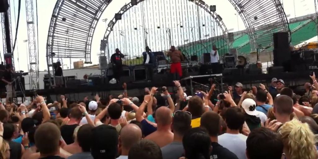 Crowd with hands raised in front of an outdoor stage where D12 is performing