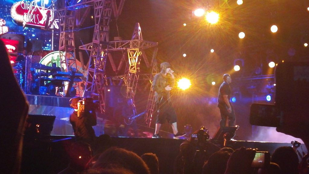 Eminem and Dr. Dre performing together on a brightly lit festival stage