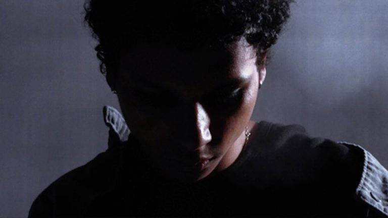 kateo in a still from the "My Love" music video, head bowed under low light