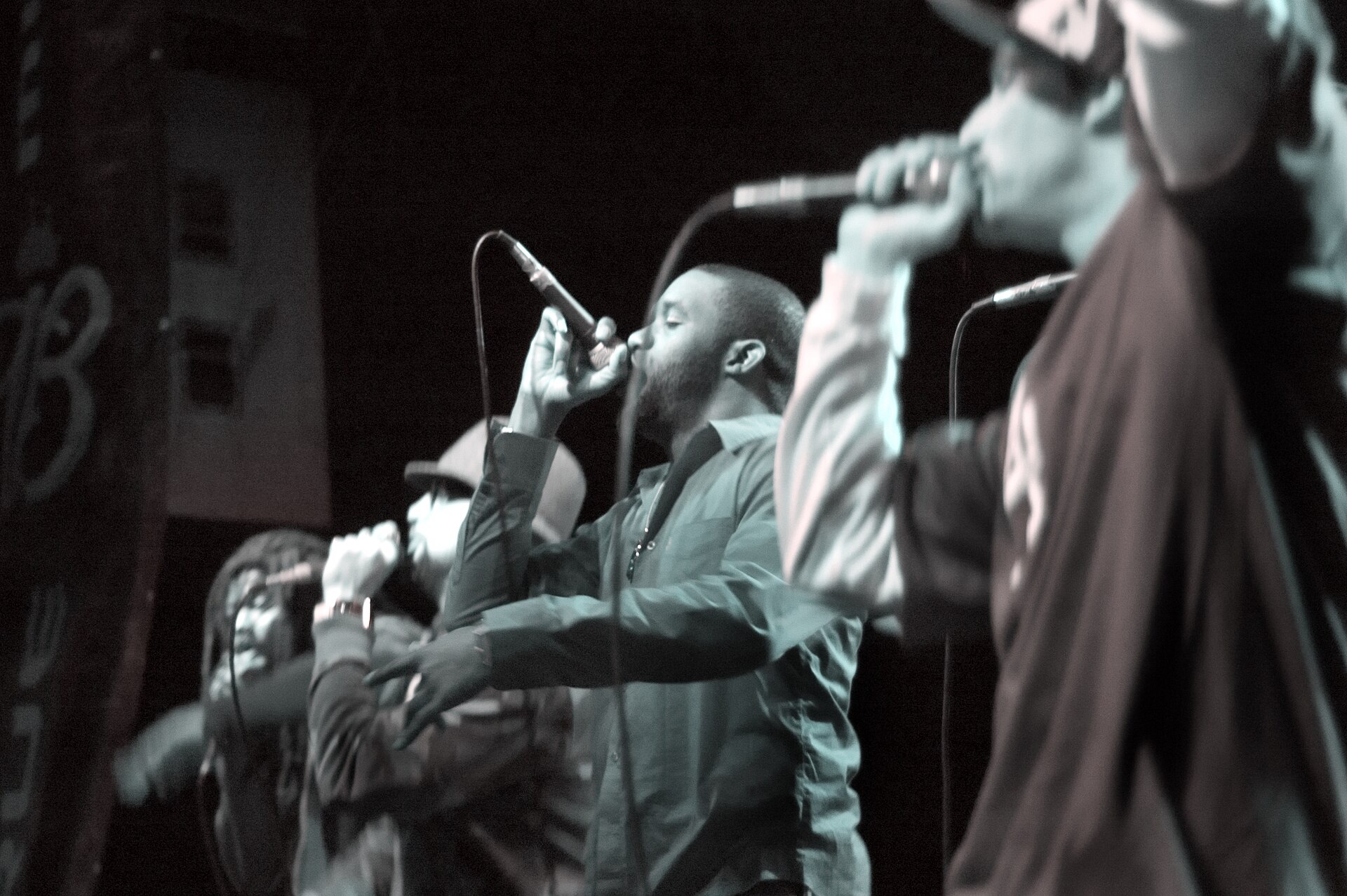Black-and-white photo of L.A. Symphony members rapping into microphones on a club stage