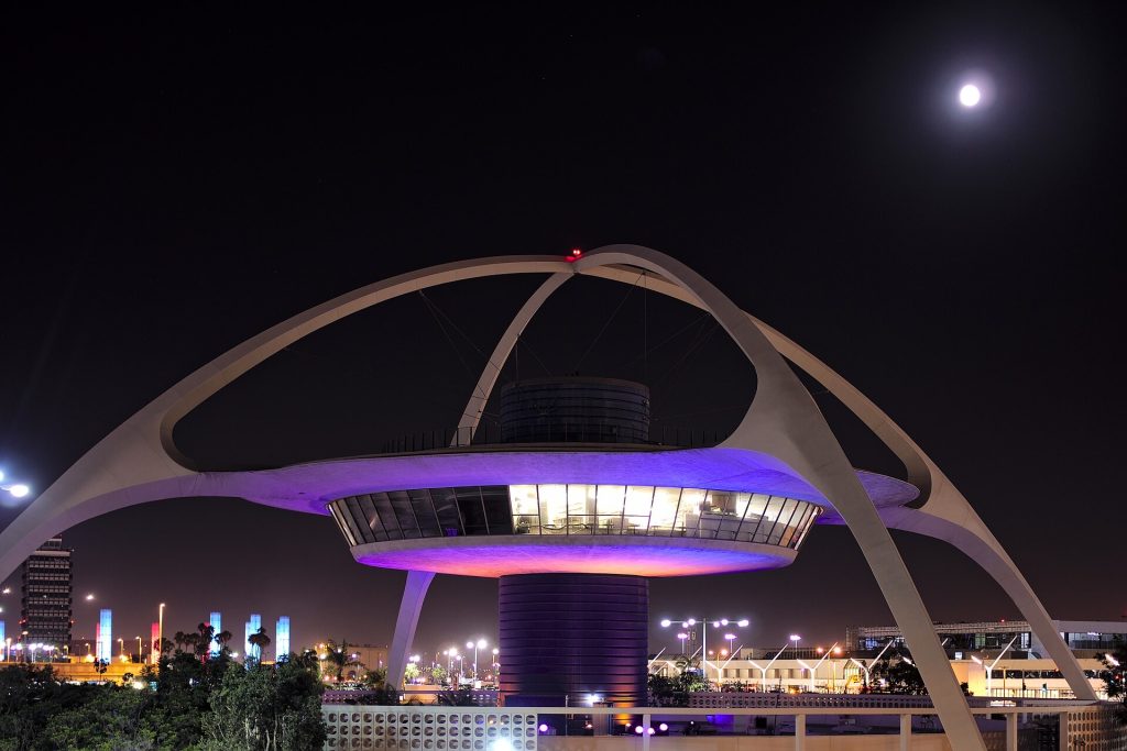 The Theme Building at Los Angeles International Airport lit up at night under a full moon