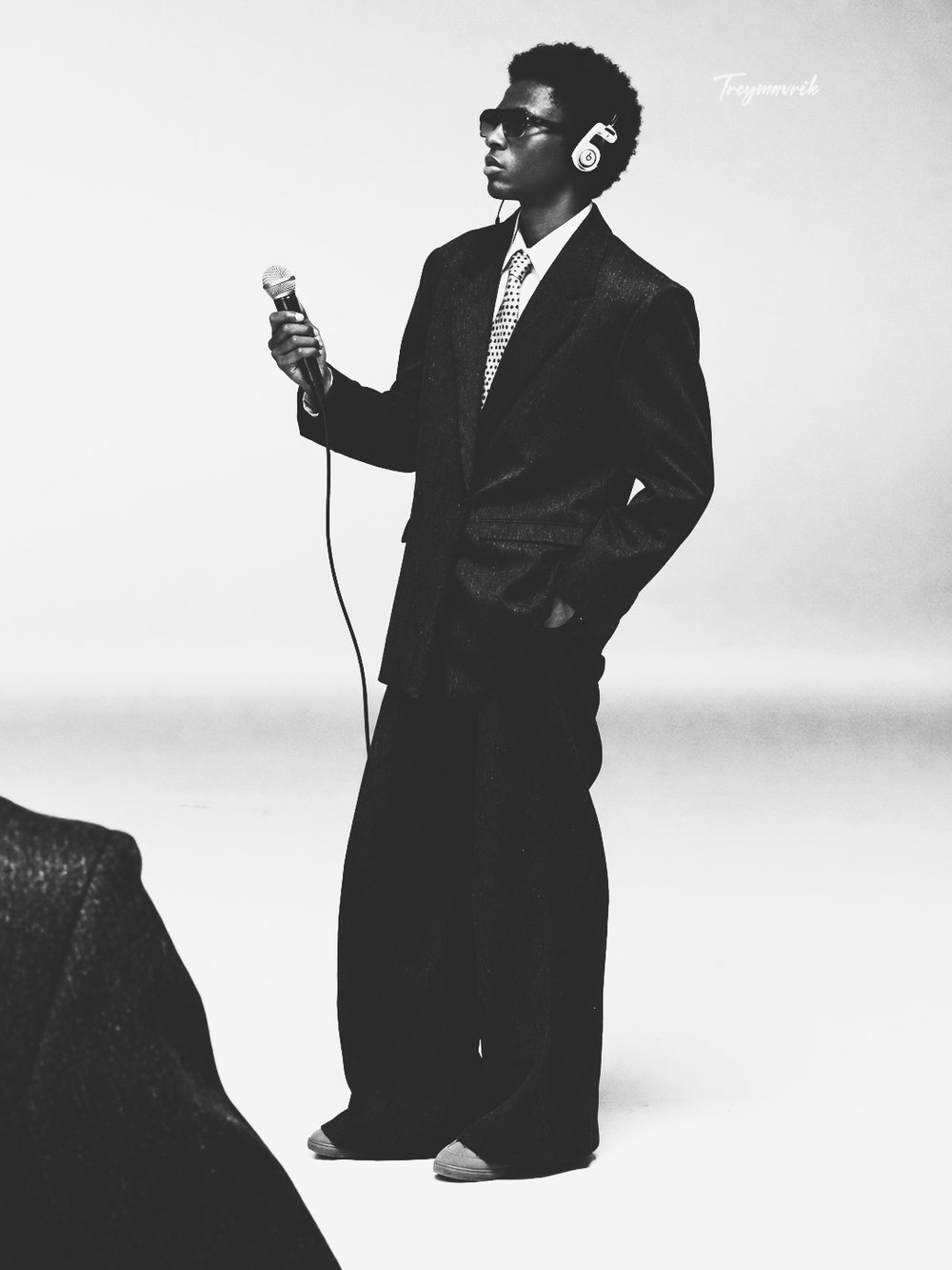 Black-and-white photo of Trey Mavrik in an oversized suit and headphones holding a microphone