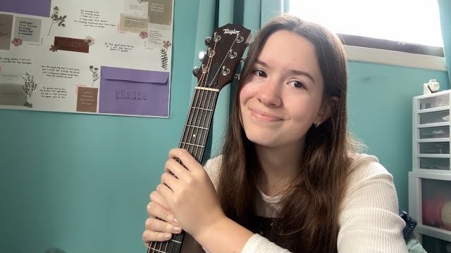 Aby Price smiling and holding her acoustic guitar