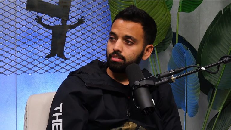 Comedian Akaash Singh seated at a podcast microphone, the former Flagrant co-host who left the show in 2026 to focus on stand-up