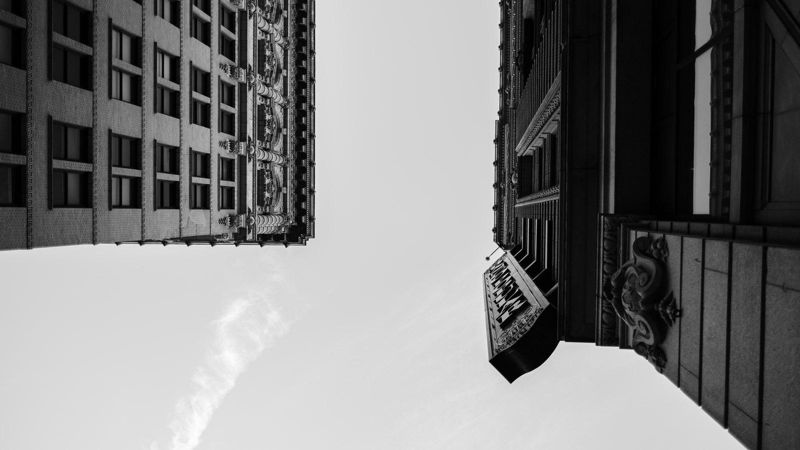 Black-and-white view looking straight up between two ornate historic towers in Downtown Los Angeles
