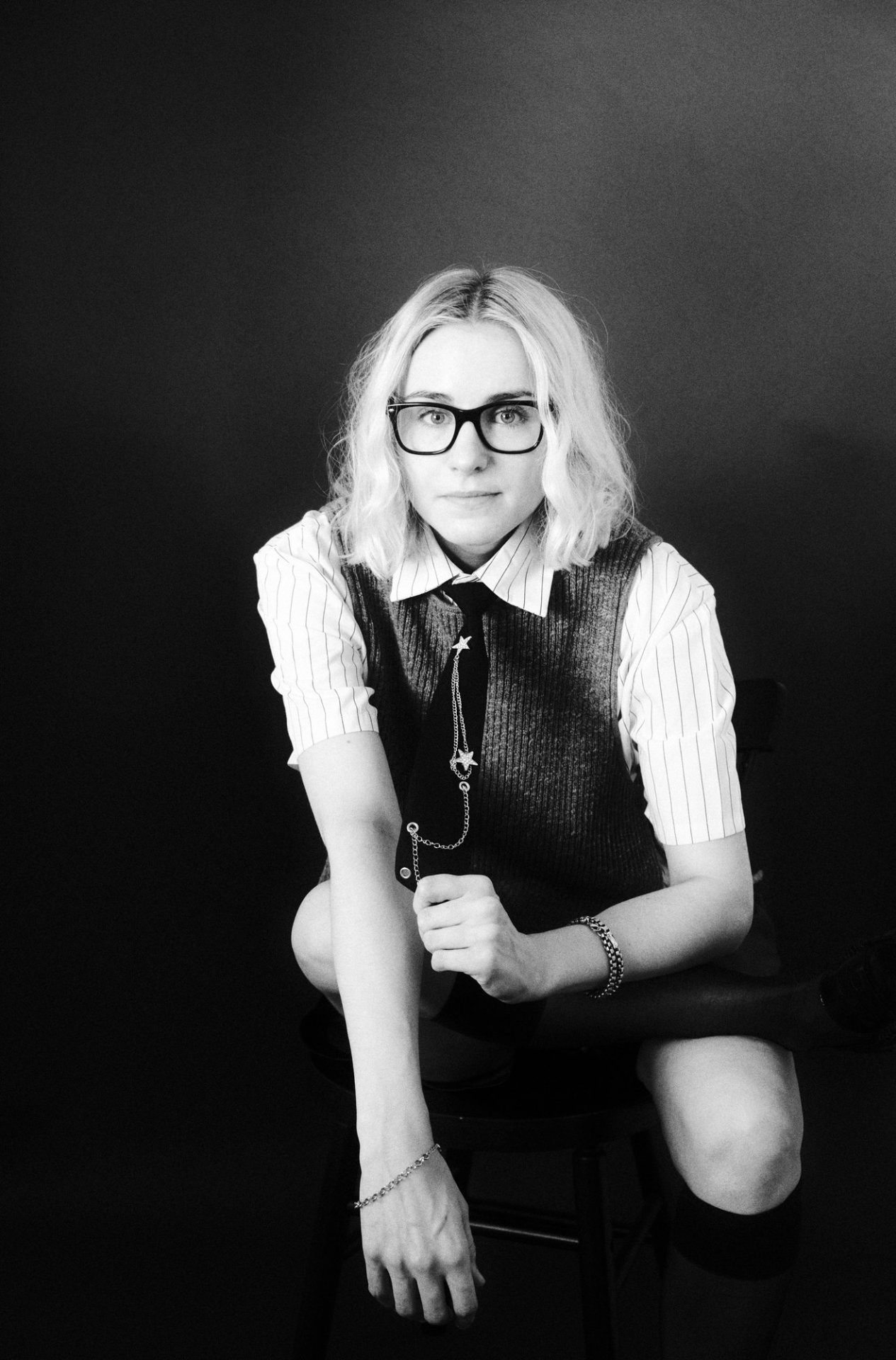 Black and white portrait of actor and voice actor Analesa Fisher in glasses, a knit vest and tie