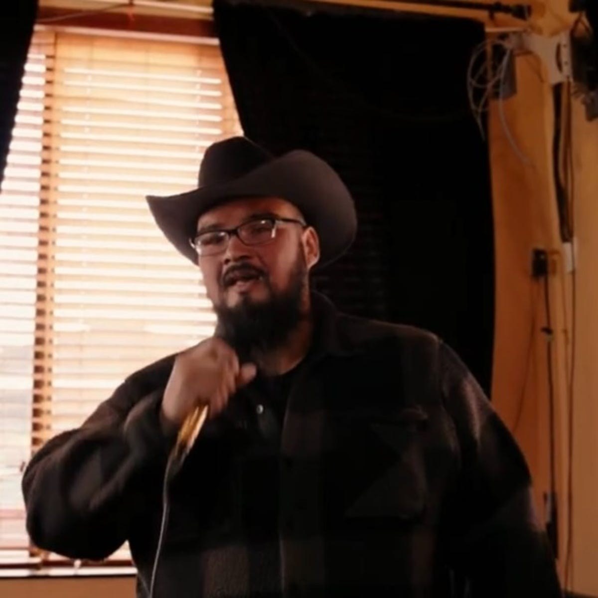 B Fabian singing into a microphone wearing a black cowboy hat