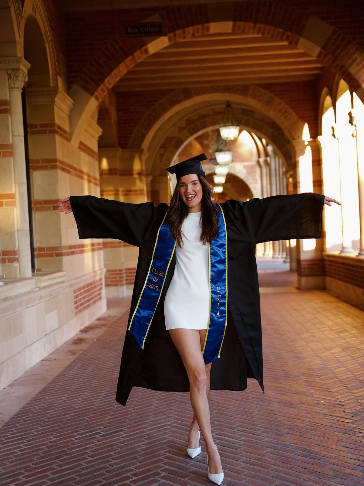 Emma Quirós in her UCLA graduation gown and Class of 2025 stole under the arches of Royce Hall