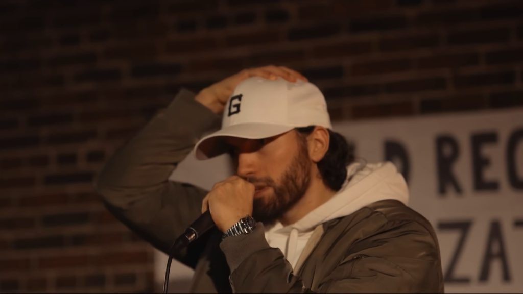 Gawne rapping into a microphone in a white G cap in the CHOPPER music video
