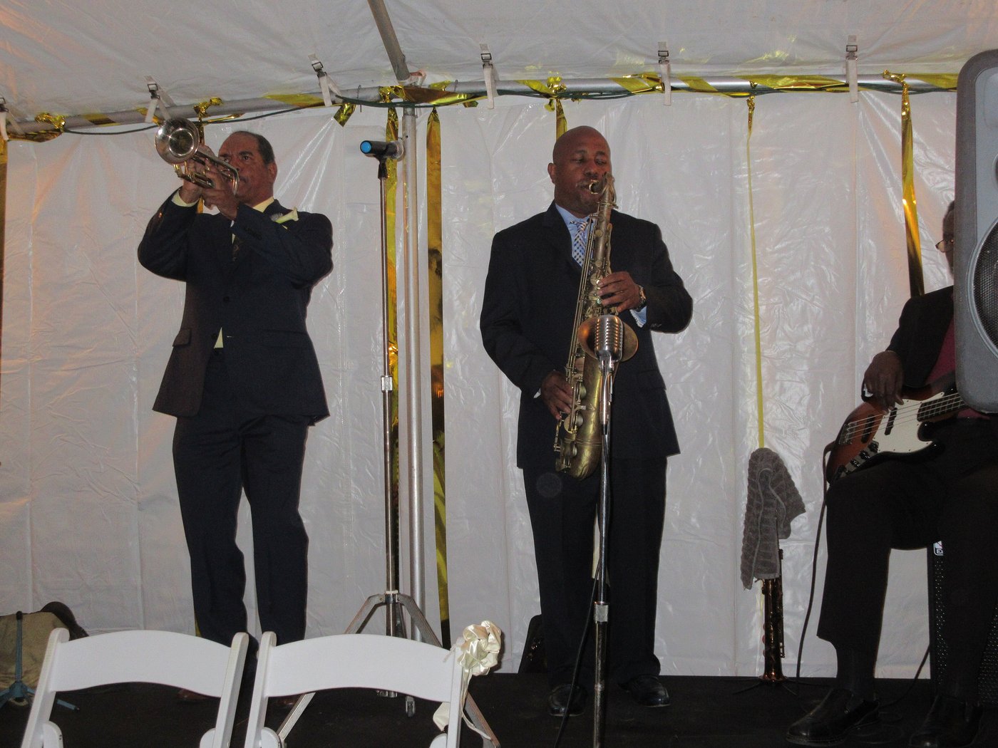 A jazz band with trumpet and saxophone playing under a wedding tent