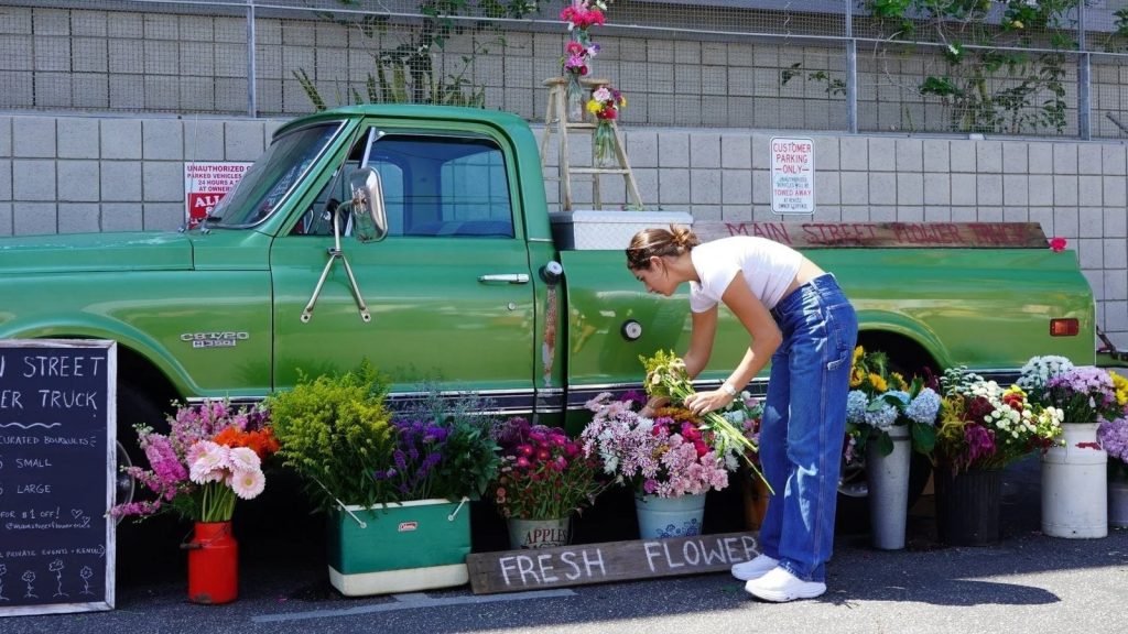 Vienna Hintze arranging bouquets beside Fiona, the green vintage pickup behind Main Street Flower Truck in Los Angeles
