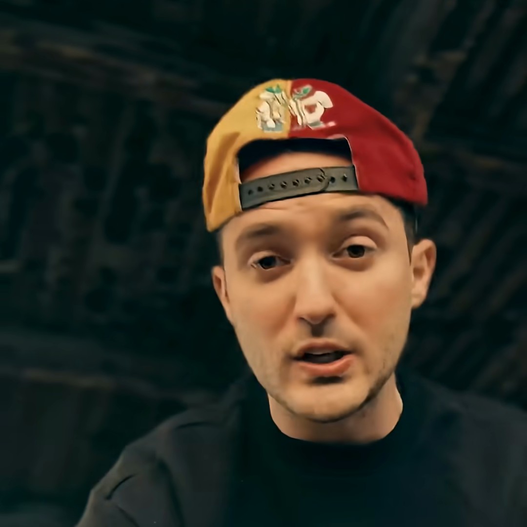 Keat rapping to the camera in a backwards cap