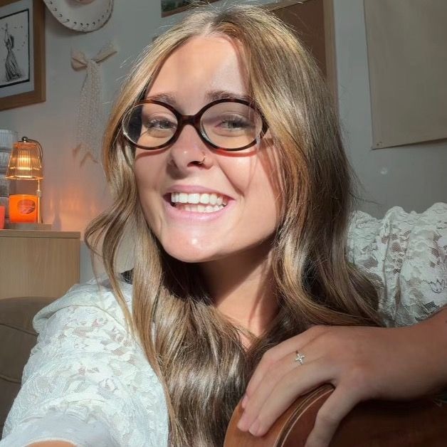 Luca Walton smiling with her acoustic guitar