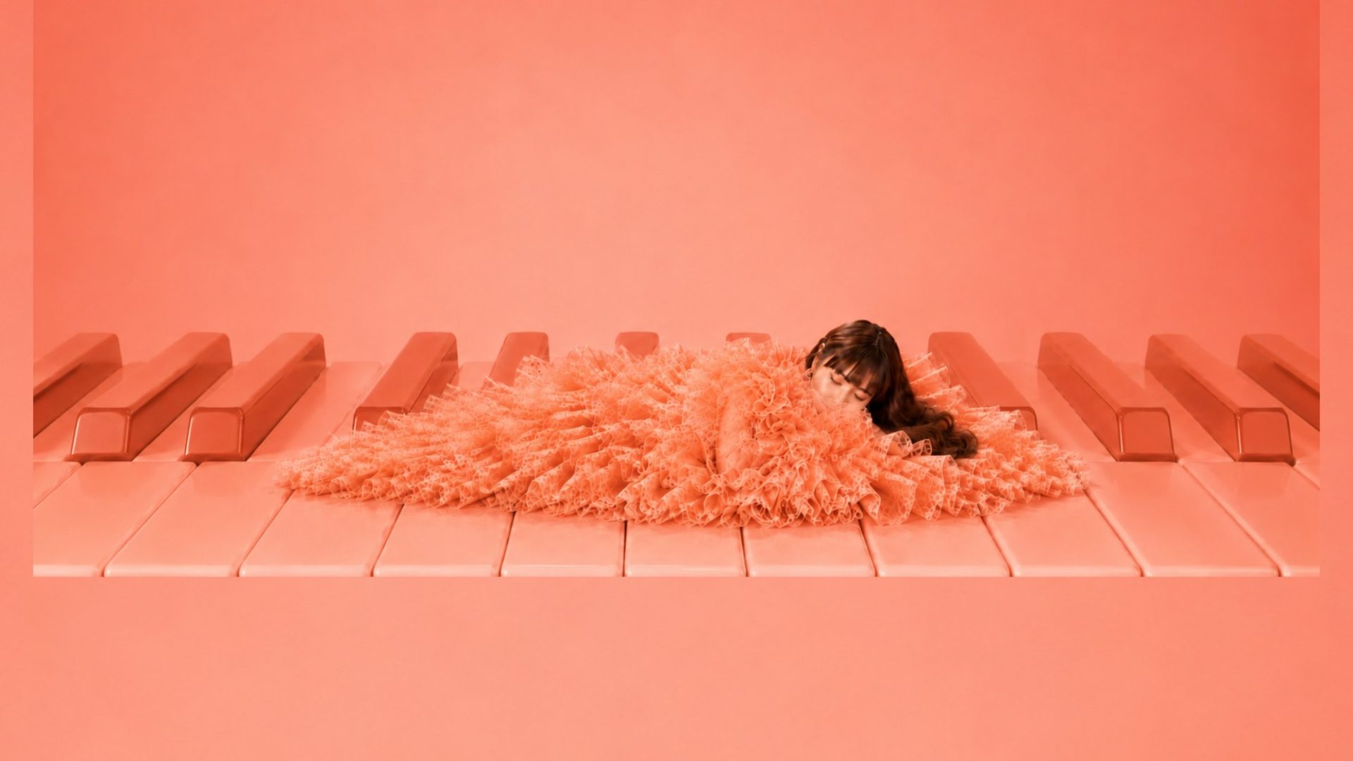 LUTILU lying in a coral feathered dress on giant coral piano keys