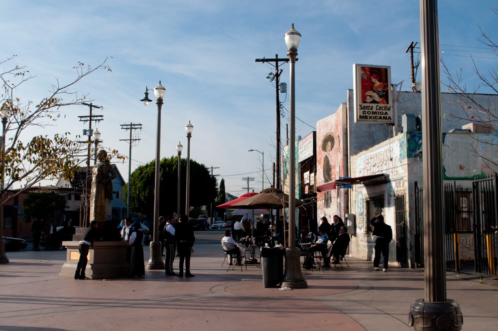 Mariachi Plaza in Boyle Heights with musicians in charro suits near a statue and an outdoor cafe