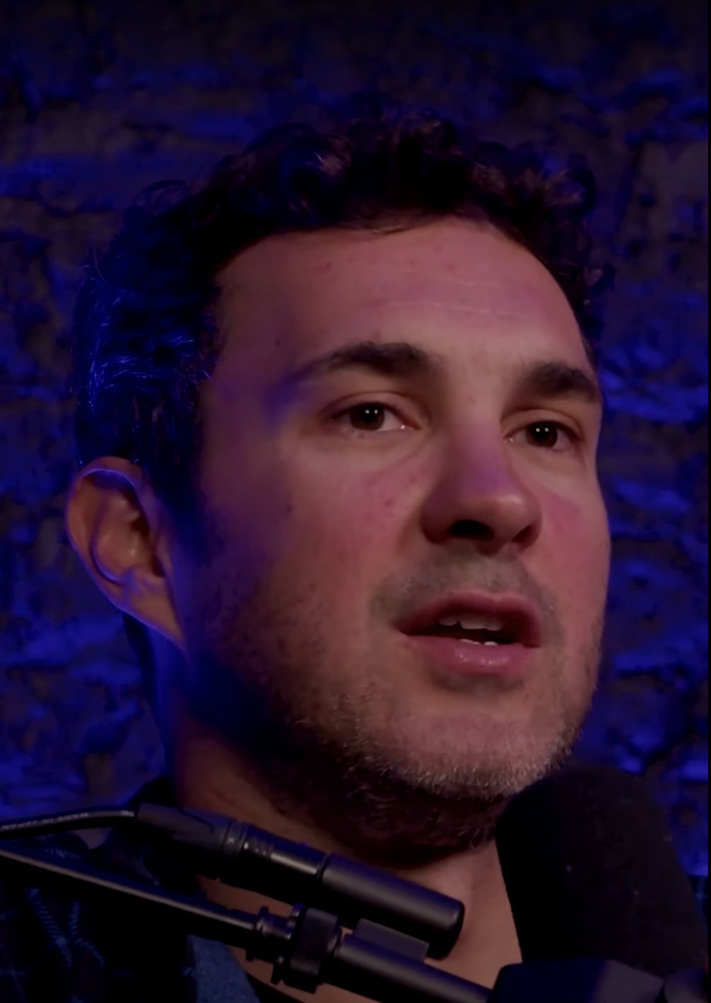 Mark Normand talking into a microphone on Neal Brennan's Blocks podcast in 2023
