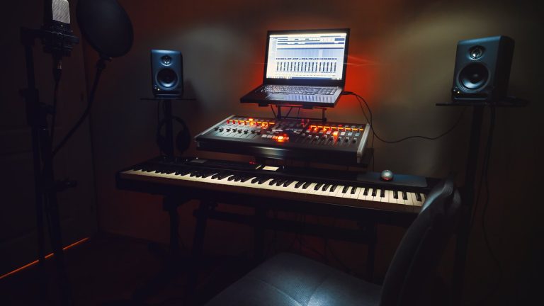 A home recording studio with a keyboard, mixer, laptop and studio monitors