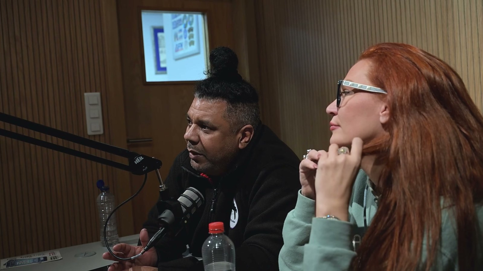 Orlando Leyba talking into a podcast microphone next to comedian April Macie during an Armed Forces Entertainment tour in Belgium, 2026