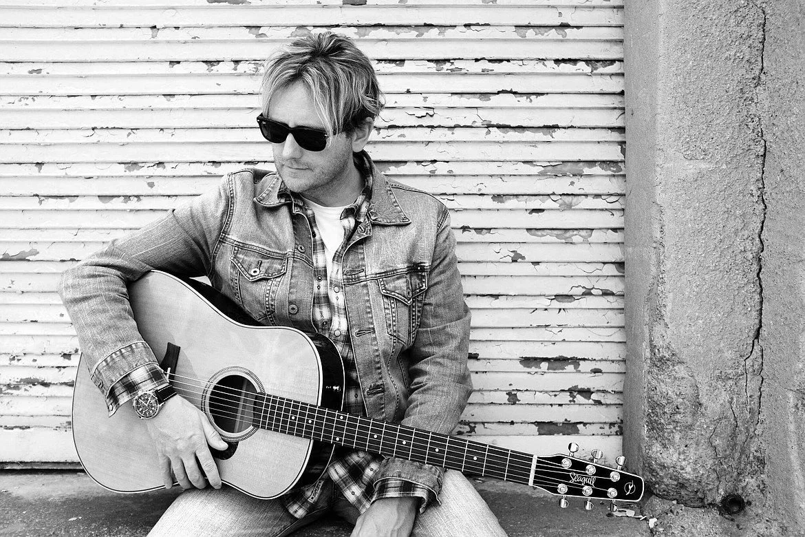 Black and white portrait of Scott Helmer with an acoustic guitar