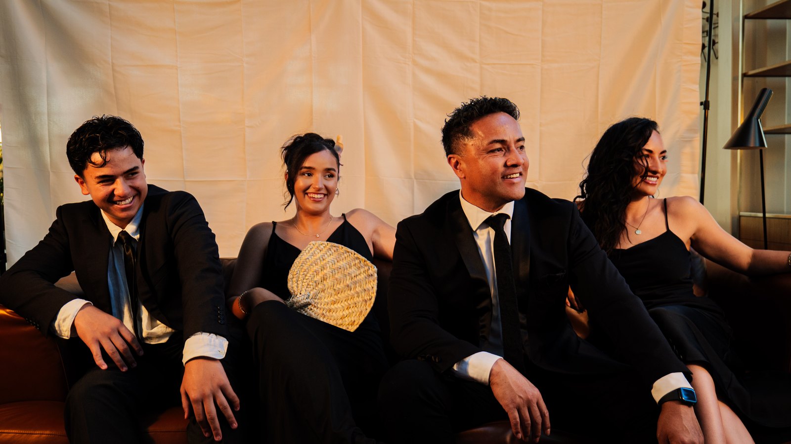 The Amosa Family in black formal wear, posed on and around a leather couch