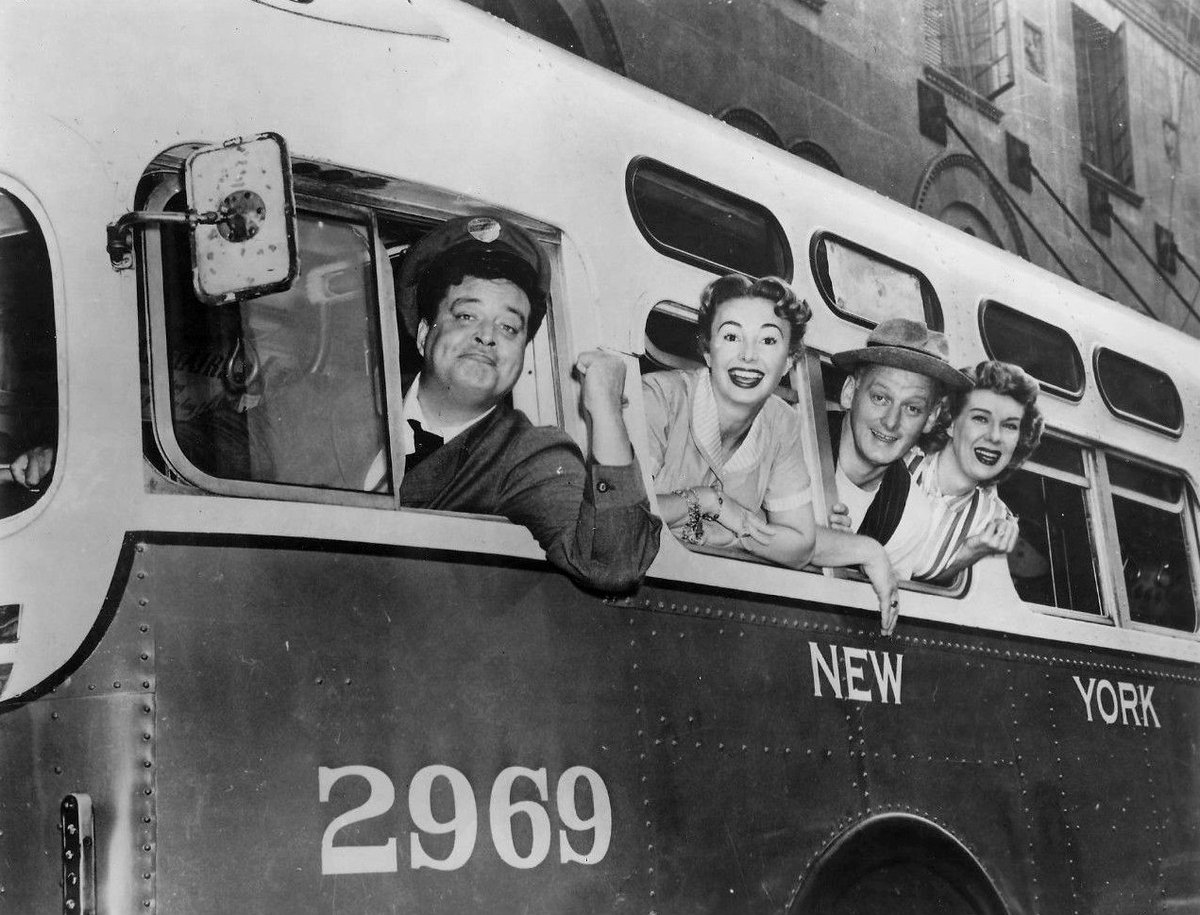 The cast of The Honeymooners leaning out of a New York city bus window, 1955