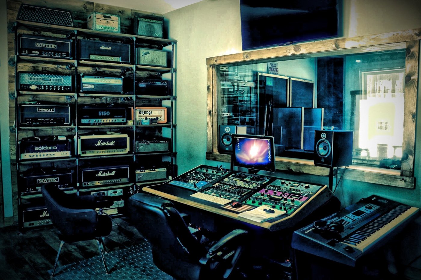 A recording studio control room with a mixing console and guitar amplifiers