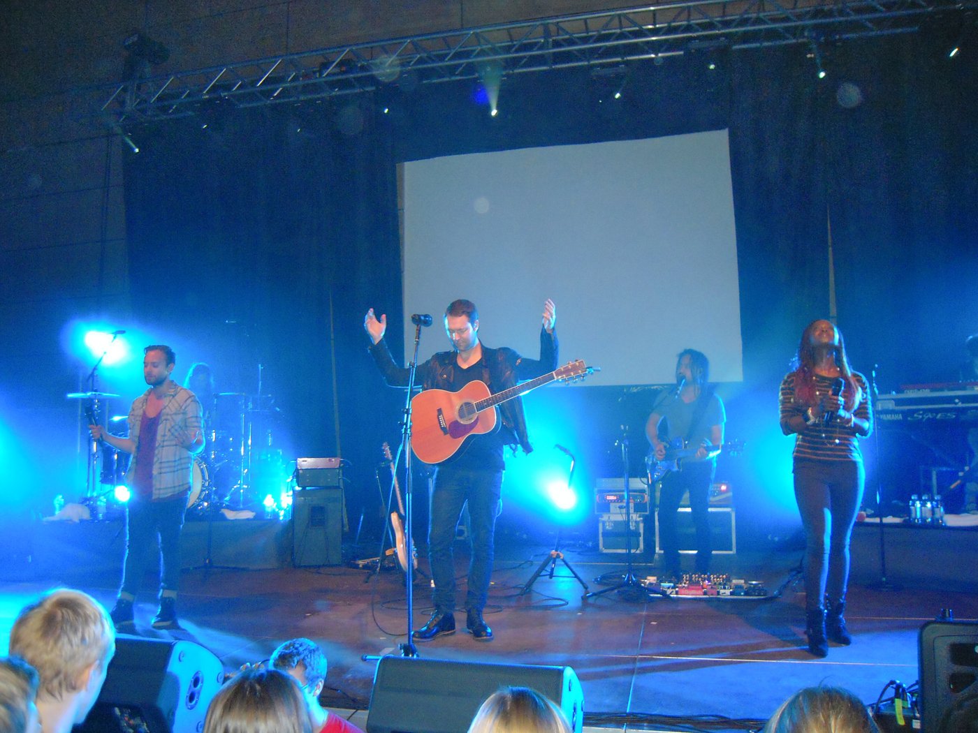 A worship band performing under blue stage lights
