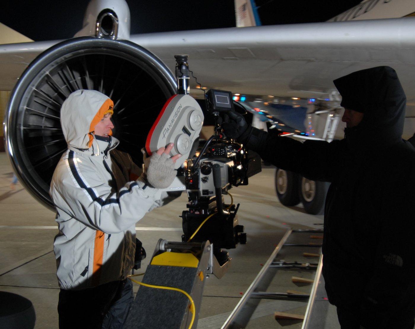 A camera operator filming next to an aircraft engine